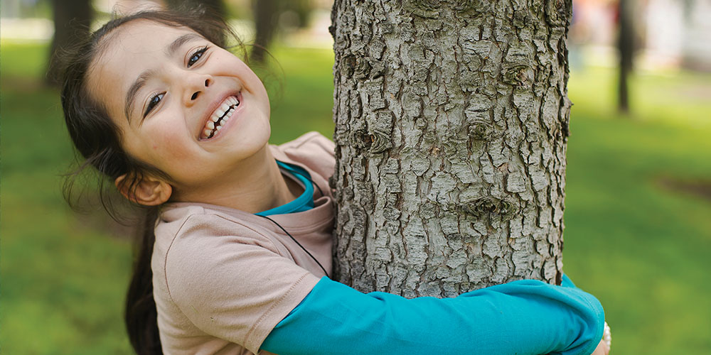 girl hugging a tree and smiling