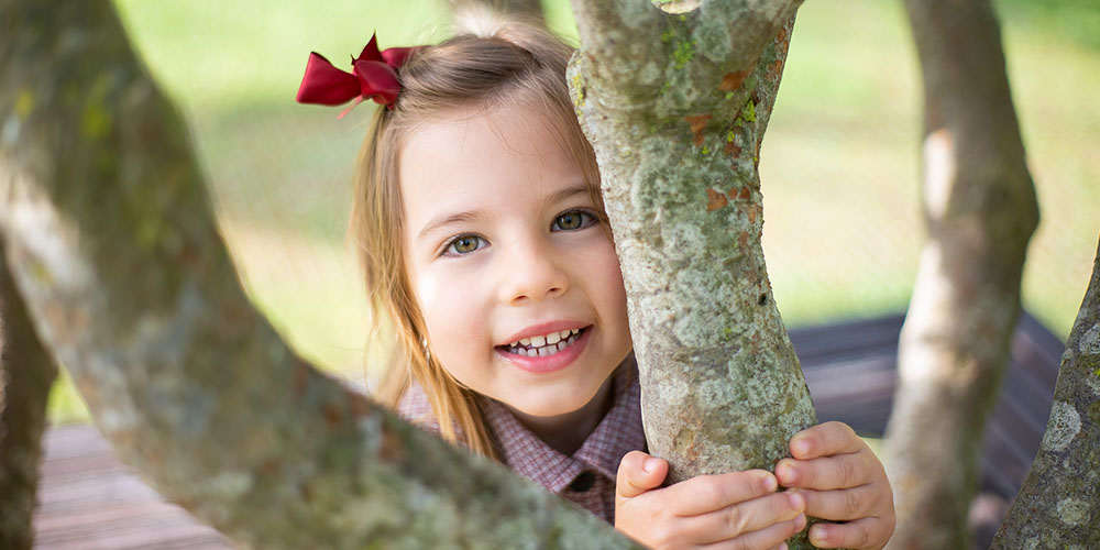 young girl hugging a tree branch