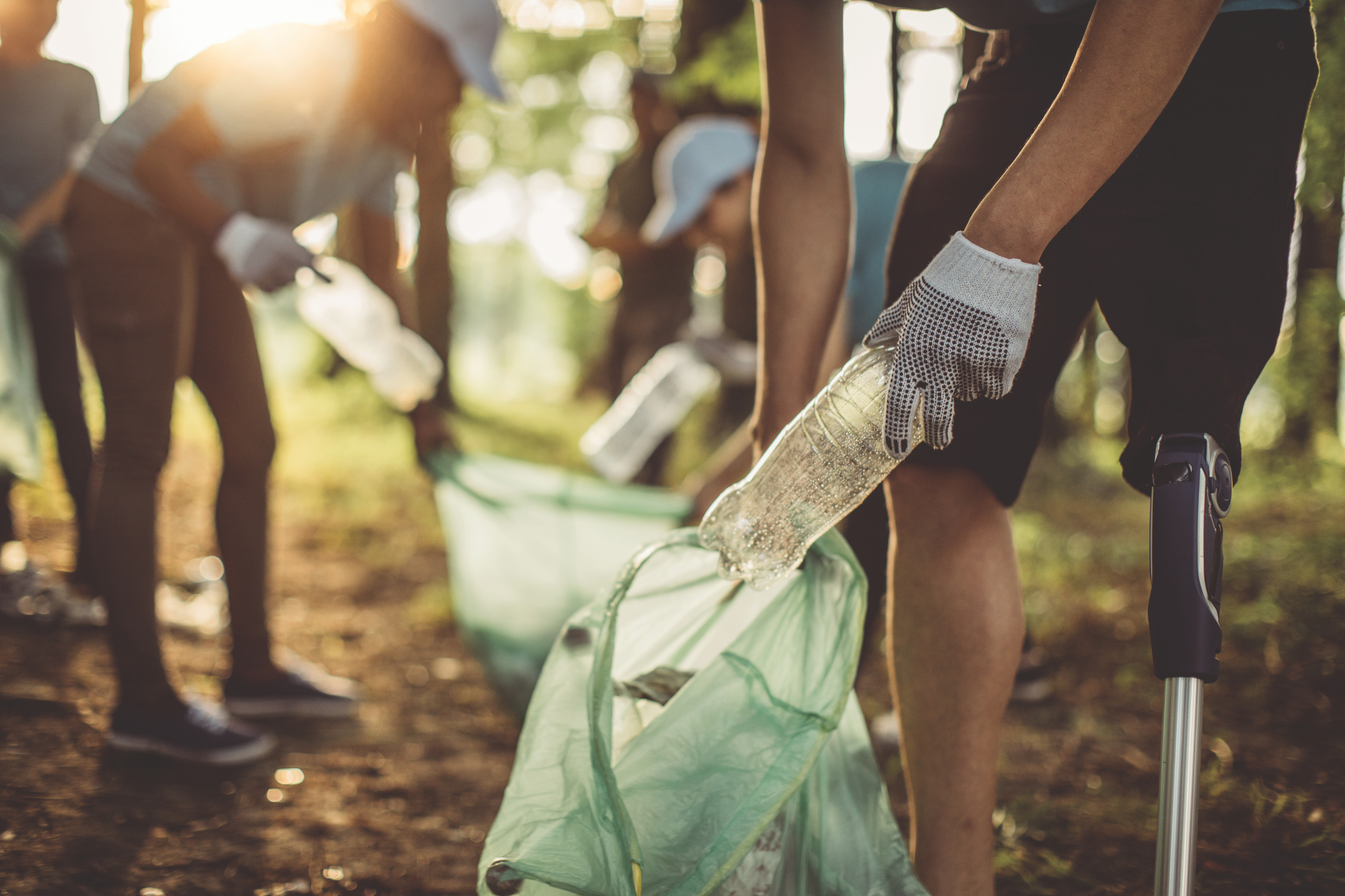Group of multi-ethnic people, people with differing abilities , volunteers with garbage bags cleaning park area