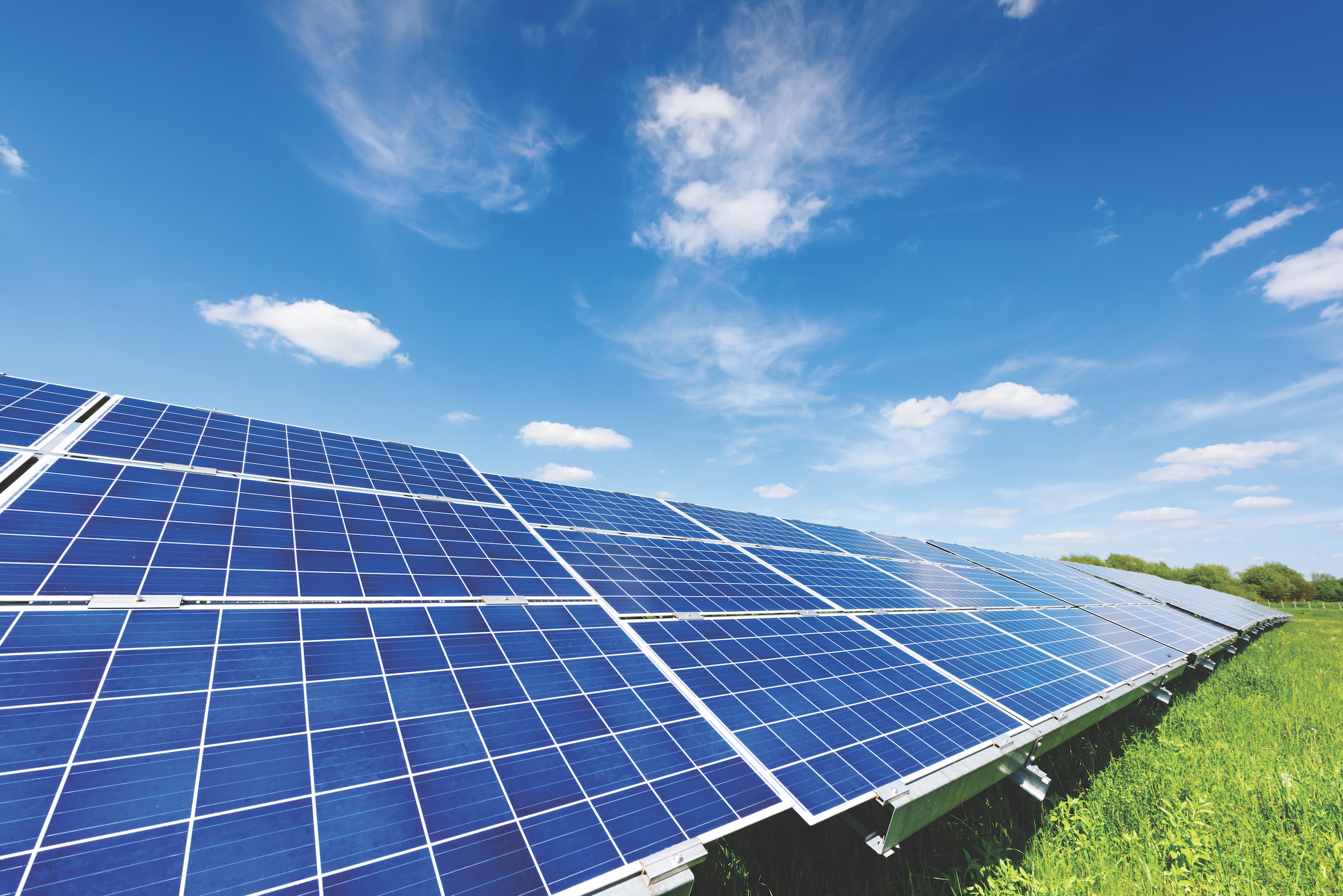 Solar panel on blue sky background. Green grass and cloudy sky. Alternative energy concept