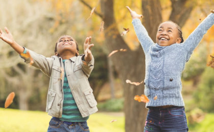 Portrait of young children throwing leaves around on an autumns day