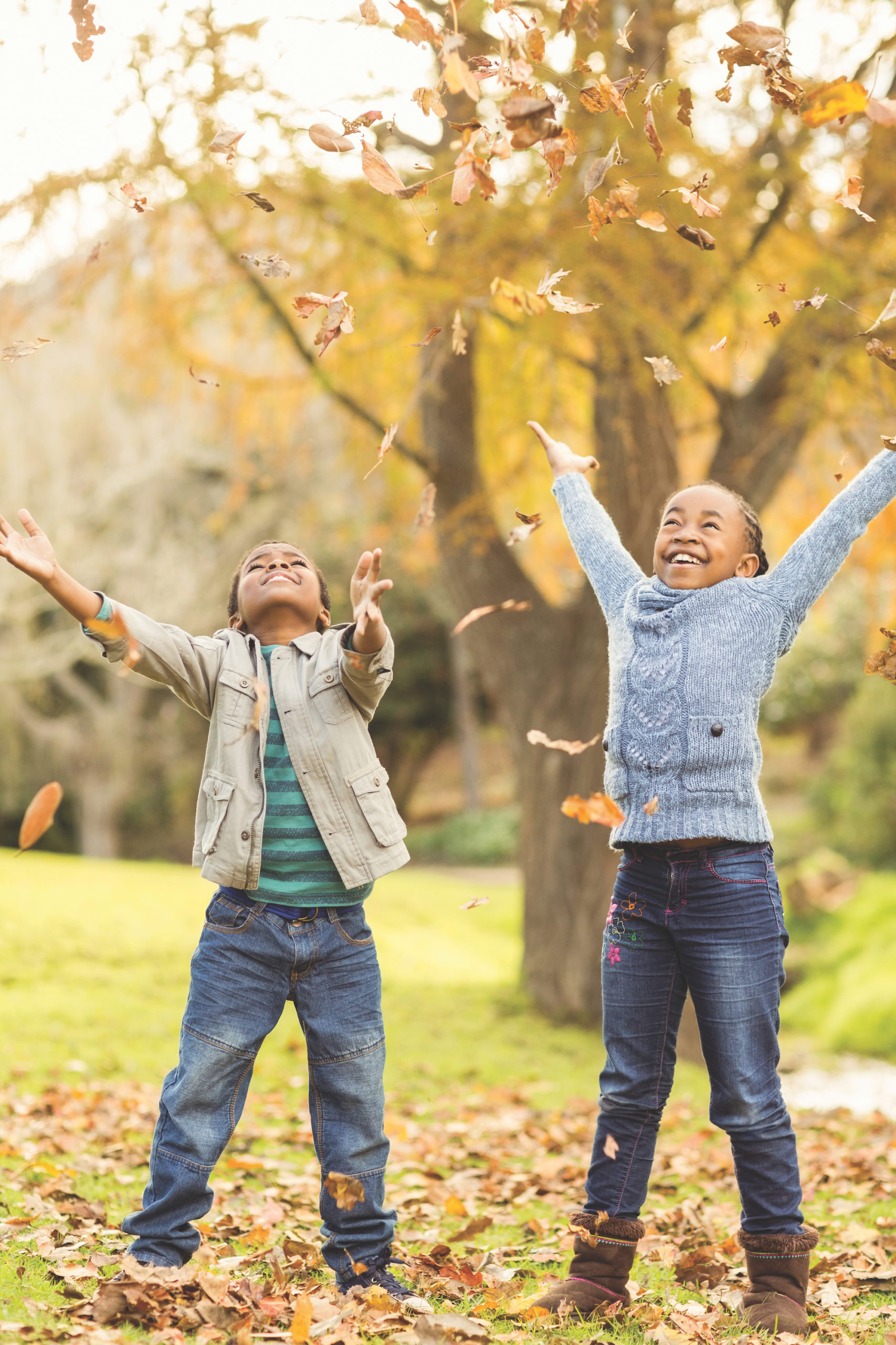 Portrait of young children throwing leaves around on an autumns day