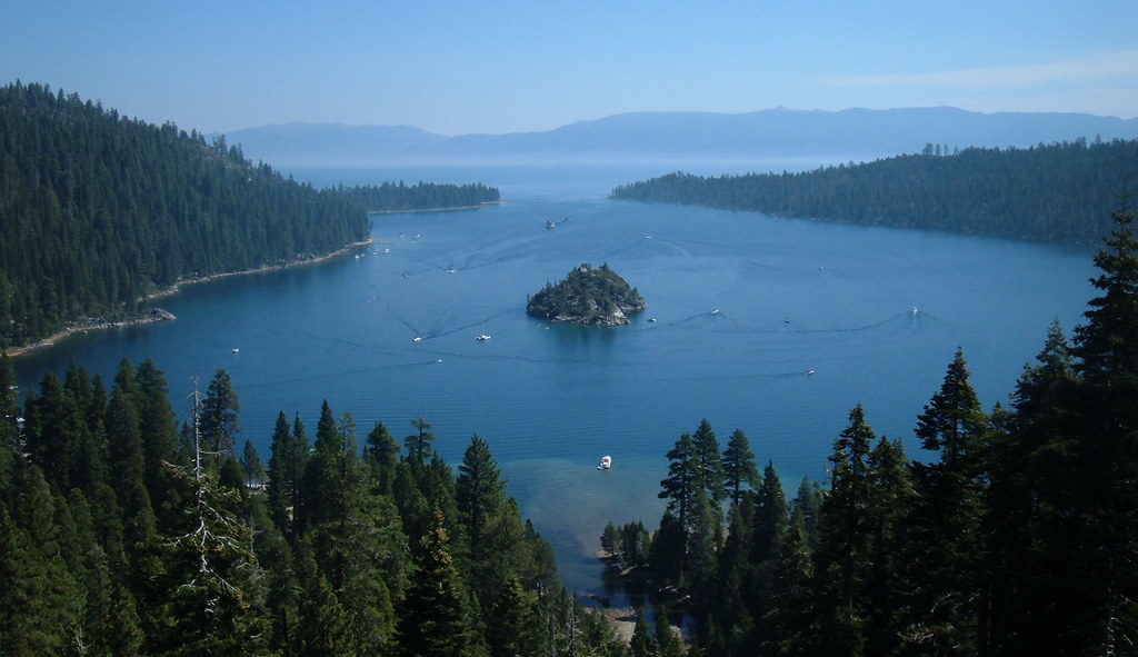 photo of emerald bay a small forested island sits nestled in a evergreen forested half circle of land surrounding a bright blue bay