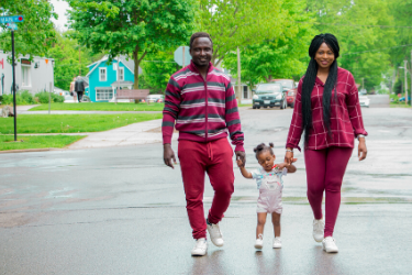 two parents and their young child take a walk around the neighborhood
