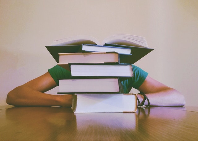 student behind a stack of books