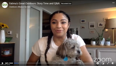 zoom screenshot of a young african american woman with a grey dog in her lap
