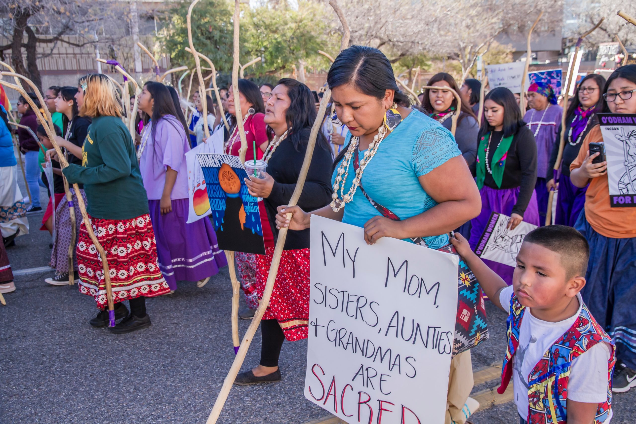 women stand in protest holding signs saying my mom sisters aunts and grandmas are sacred