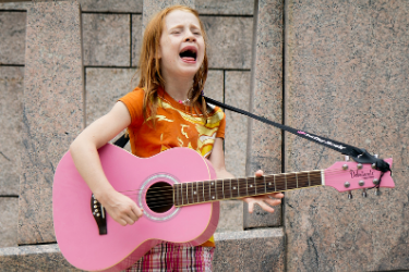 girl singing with a pink guitar