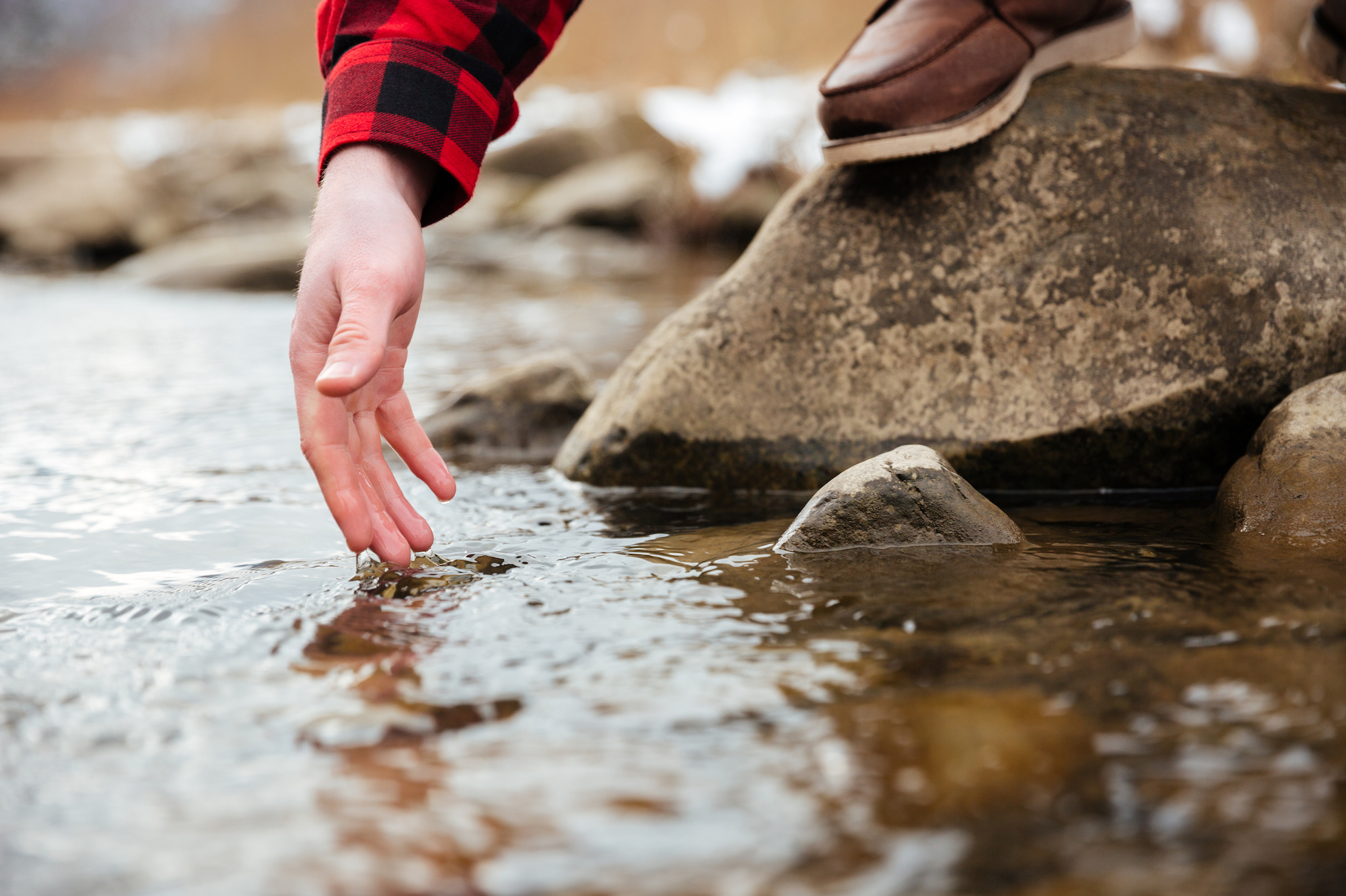 Closeup portrait of a male hand testing water in river