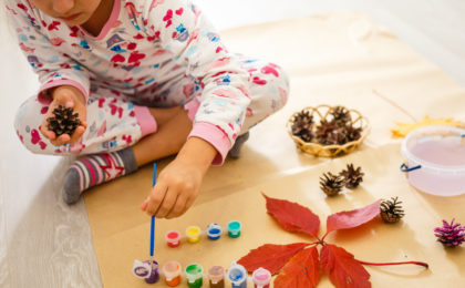 little girl is painting the color on pine cones