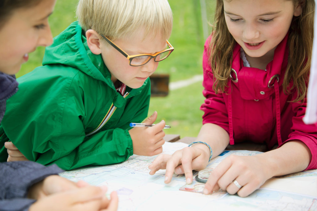 elementary students using navigation tools outdoors