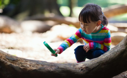 young girl holding a magnifier and looking the tree in the summer forest morning