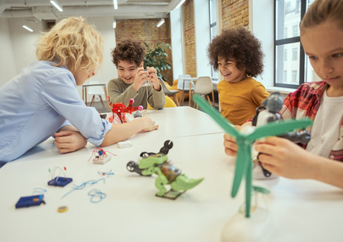 Children examining technical toys while sitting together at the table during STEM class. Engineering, afterschool activity.