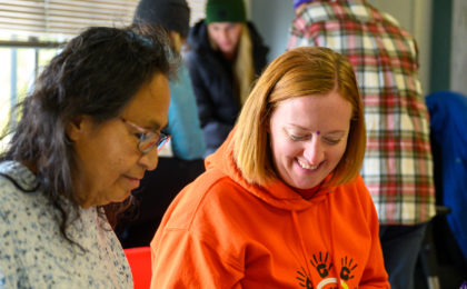 Two educators look at a tree cross section cutting inside a classroom