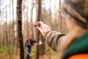 Young adult woman holds a prism in front a trees