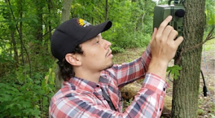 Man operates a device on a tree in a forest