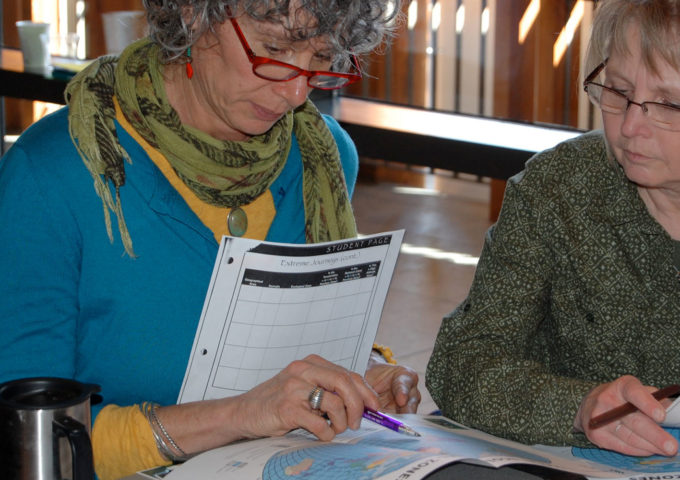 Two women review teaching materials together at a table