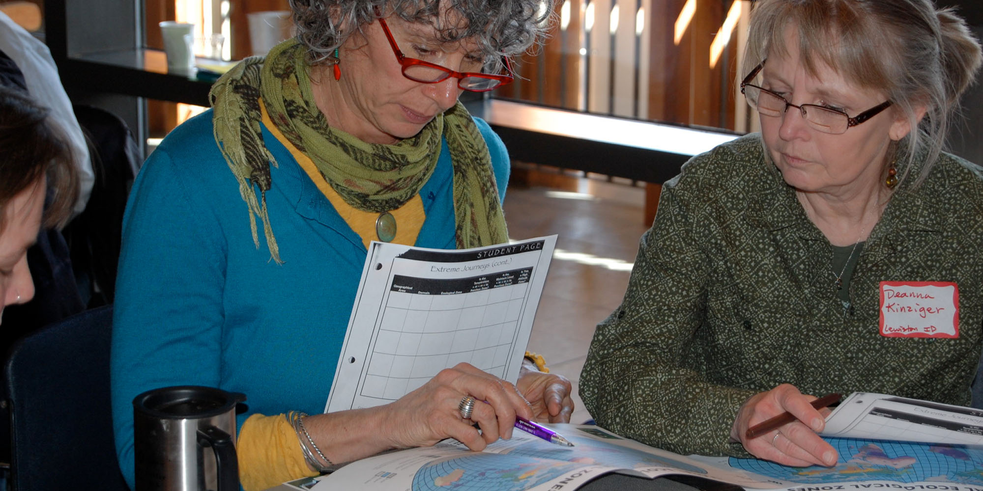 Two women review teaching materials together at a table