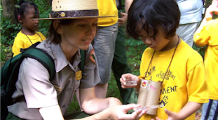 Female park ranger helps a young child